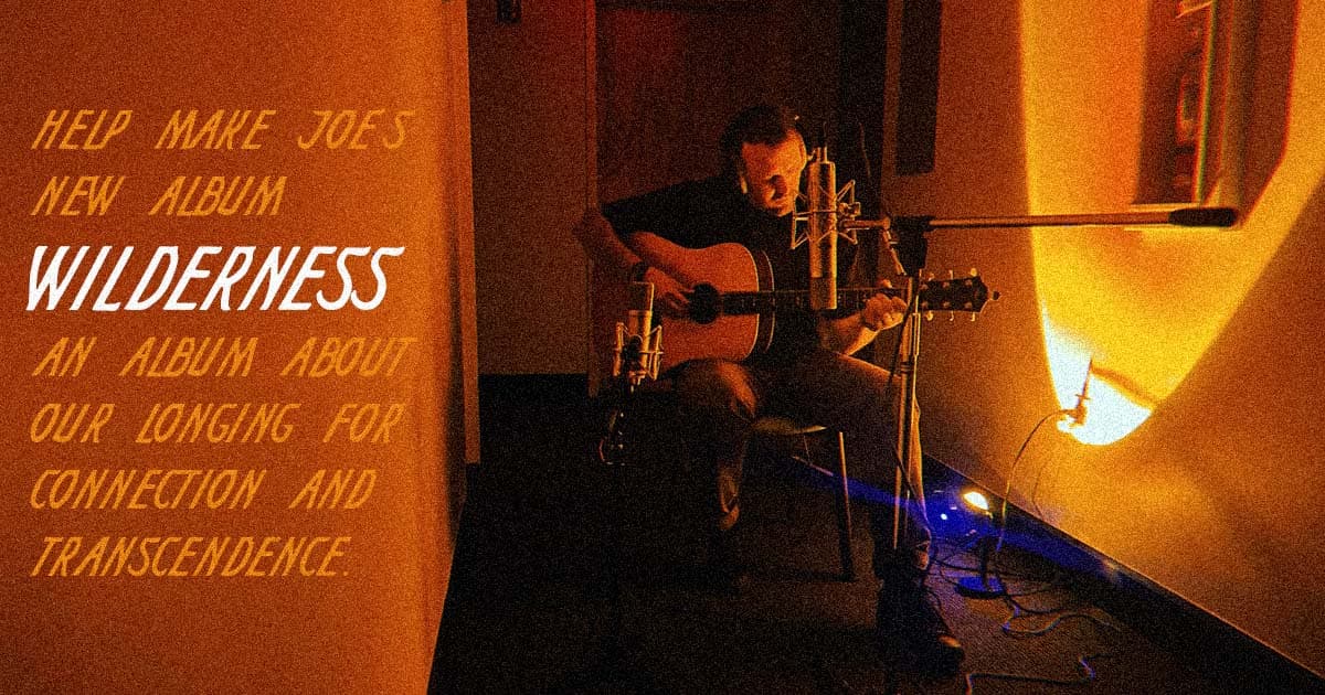 An image of Joe Day recording acoustic guitar in a hallway (which is an unusual place to do that) with the caption 'Help make Joe's new album Wilderness. An album about our longing for connection and transcendence.'